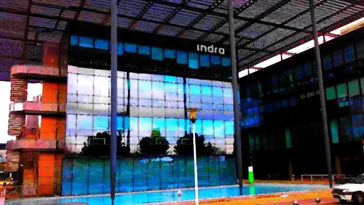 Fachada de cristal de colores de la sede de Indra en San Fernando de Henares, con el logotipo de la empresa en lo alto